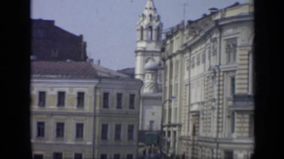 1971 Moscow street scene with a domed church tower, historic facades, cars, pedestrians, and visible 8mm frame edges.