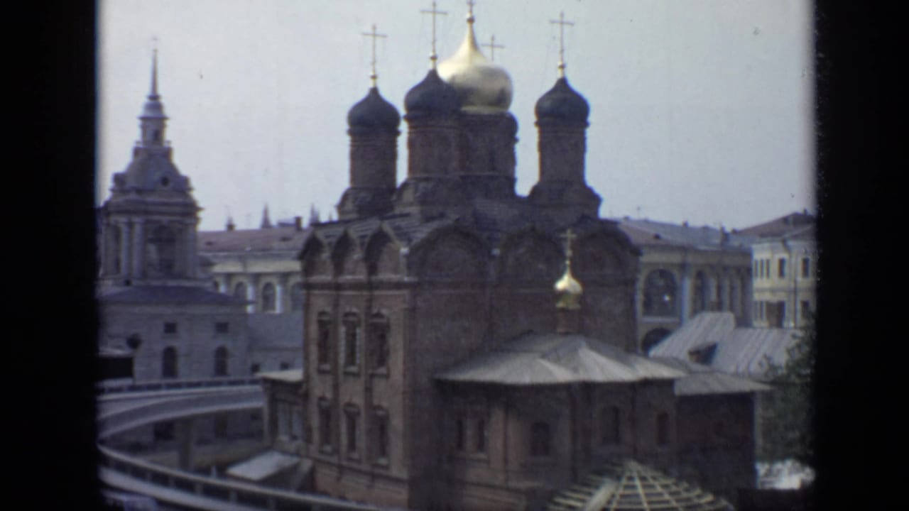 Russian Orthodox church with onion domes and crosses seen through dark window framing.
