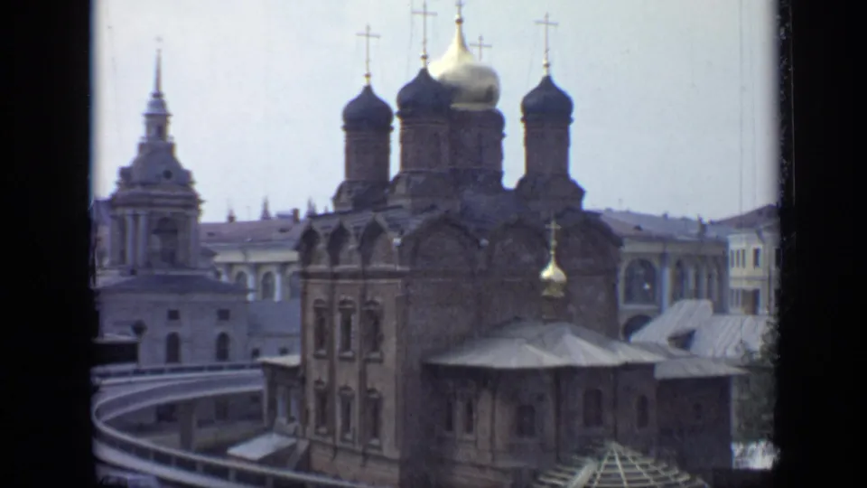 1971 Moscow 8mm frame with the cathedral centered, onion domes rising above brick walls and pale urban buildings.
