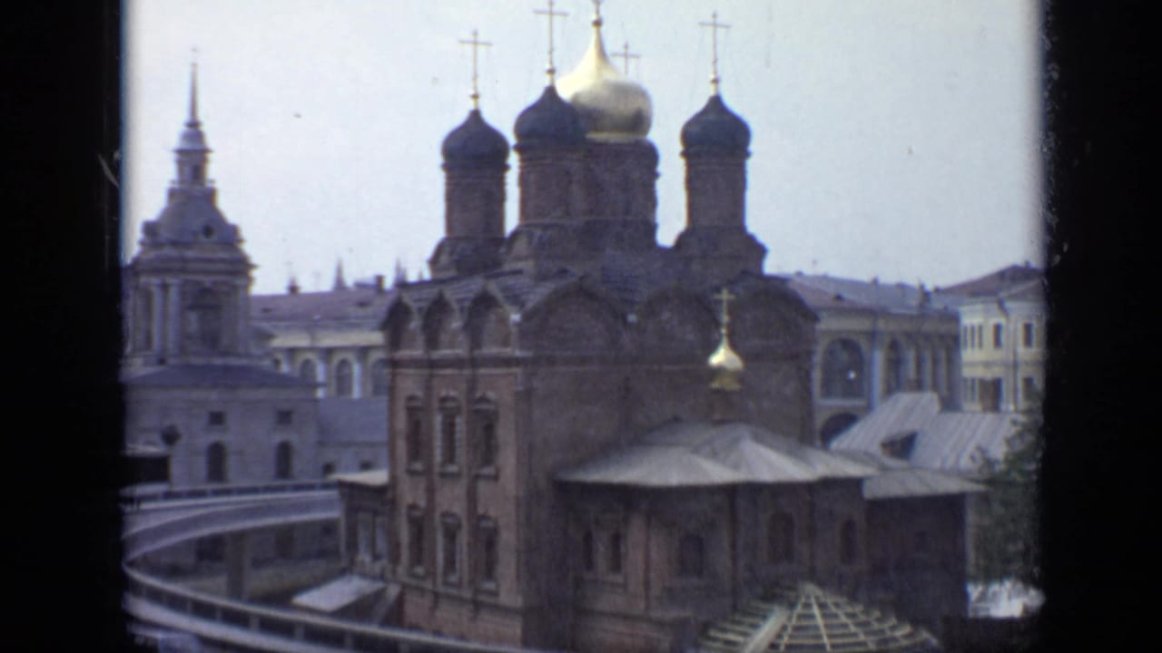 1971 Moscow 8mm frame showing historic church architecture with onion domes, crosses, and adjacent spires viewed from an elevated angle.
