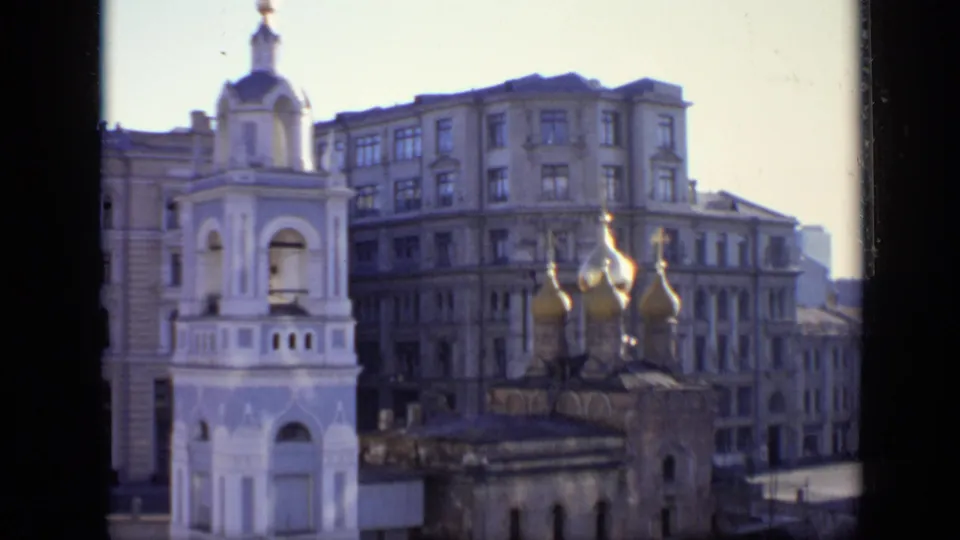 1971 Moscow architectural view with a white bell tower, golden onion domes, and tall surrounding residential or civic buildings.