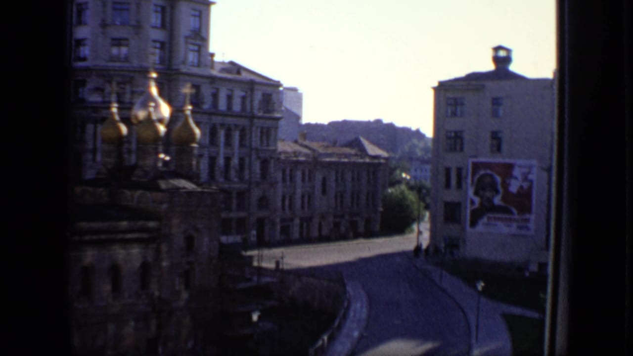 Moscow street scene with golden church domes, tall buildings, a curved road, and a large Soviet-era poster on a facade.