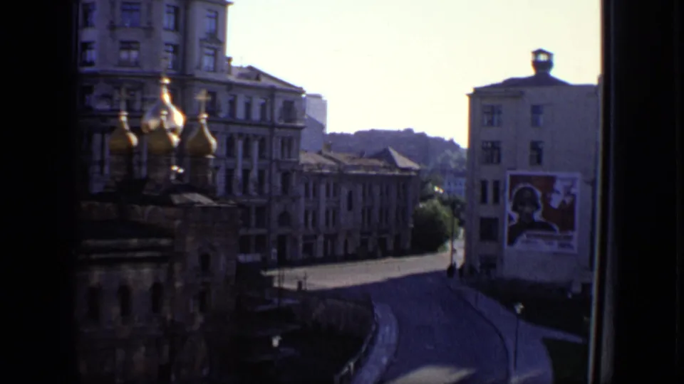 Moscow street scene with golden church domes, tall buildings, a curved road, and a large Soviet-era poster on a facade.