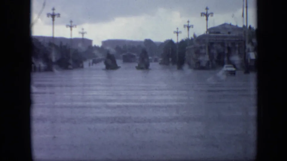 1971 Moscow street scene with floodwater covering a wide road, lampposts lining the view, dark trees, and a small car in the distance.