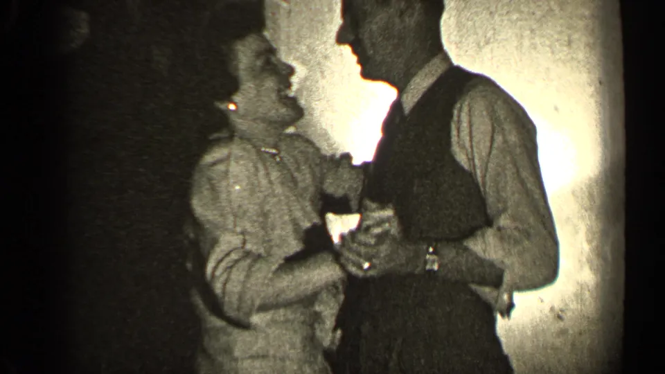 In 1947 Illinois home-movie footage, an adult couple dances closely indoors beside a lit wall.