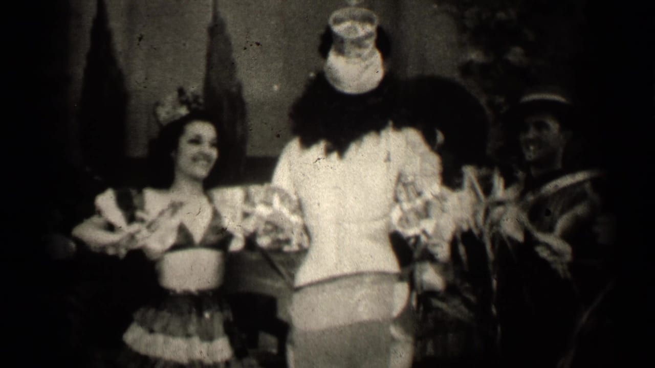 Woman in grass skirt smiles as the clown-costumed performer turns toward performers at right.