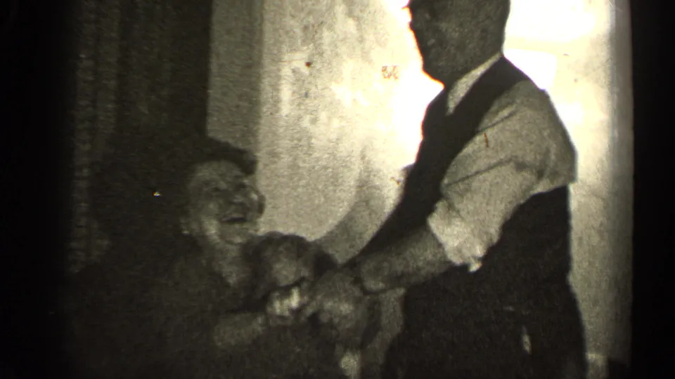The older woman appears to smile broadly as the older man reaches toward her in grainy 8mm footage from Illinois in 1947.