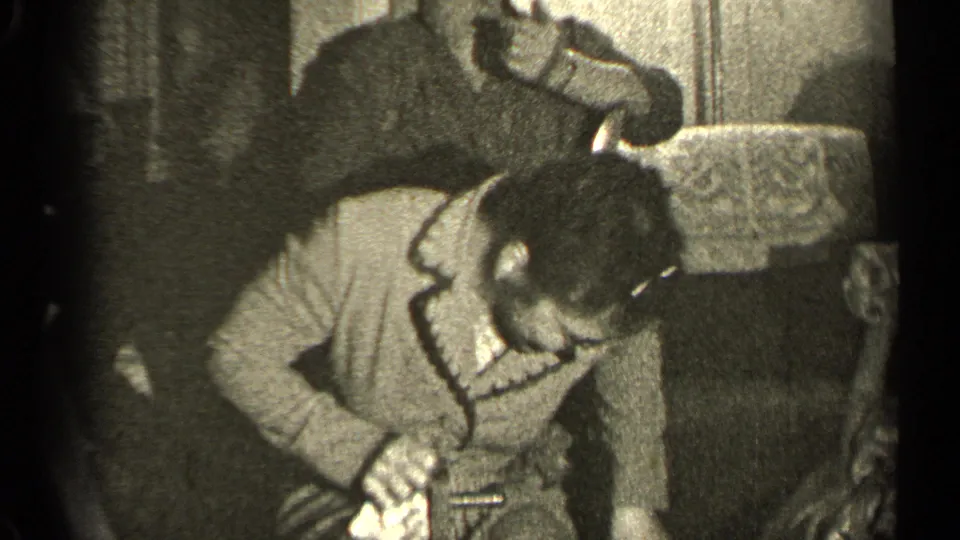 The woman leans forward in a 1947 Illinois interior while another adult figure reaches near the chair behind her.