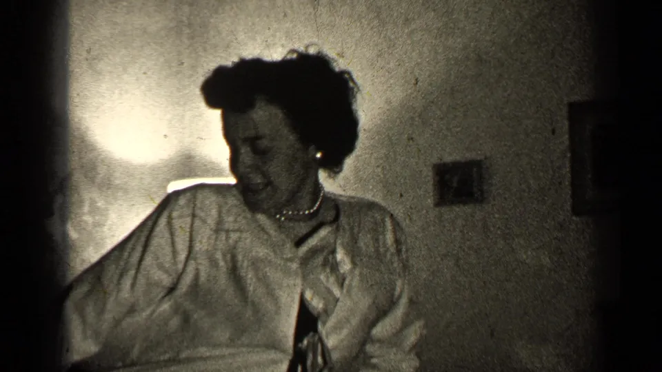 The woman bends and laughs during an energetic dance in a dim private Illinois room, with wall decor in the background.