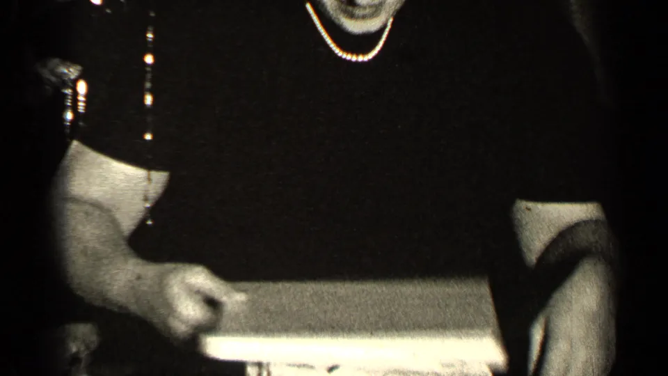 1947 Illinois Christmas frame showing an adult in a dark dress with pearls holding a wrapped package close to the camera.