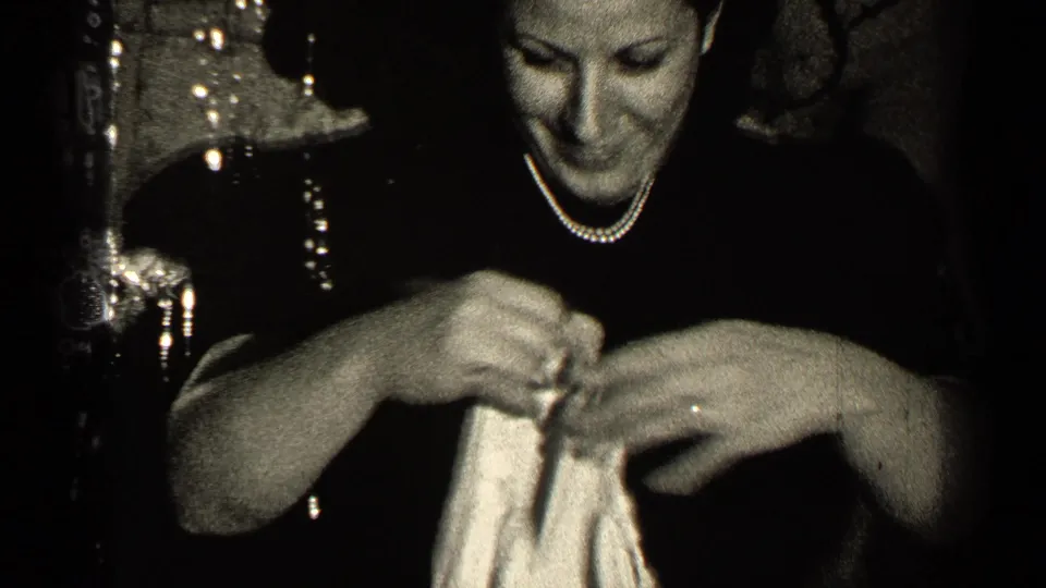 The woman smiles down at a pale garment as she handles it with both hands in the Illinois interior scene.