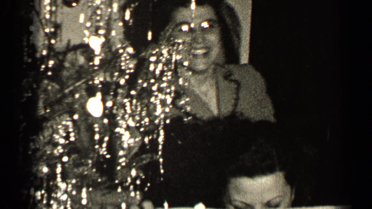 Woman laughing beside shiny decorations in a dark indoor scene.