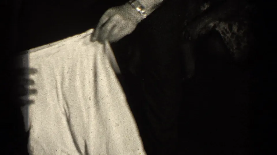 A close black-and-white frame shows hands gripping a light undergarment, consistent with the playful 1947 family moment.