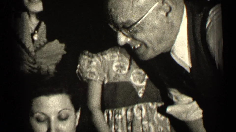 The final frame shows a man in glasses leaning over the seated or lower woman in pearls, with a young girl and other relatives nearby indoors.