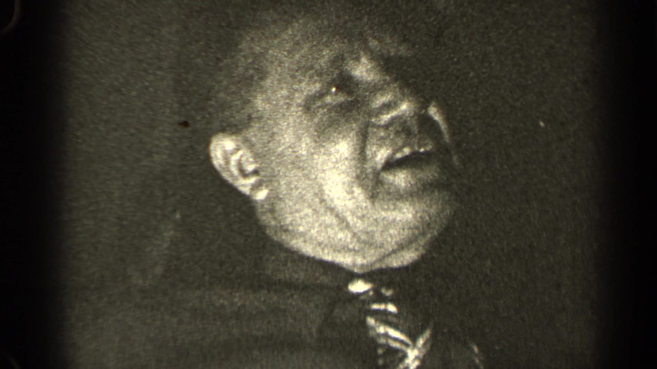 Older man in a dress shirt and patterned tie laughs in close-up, from 1947 Illinois 8mm home-movie footage.