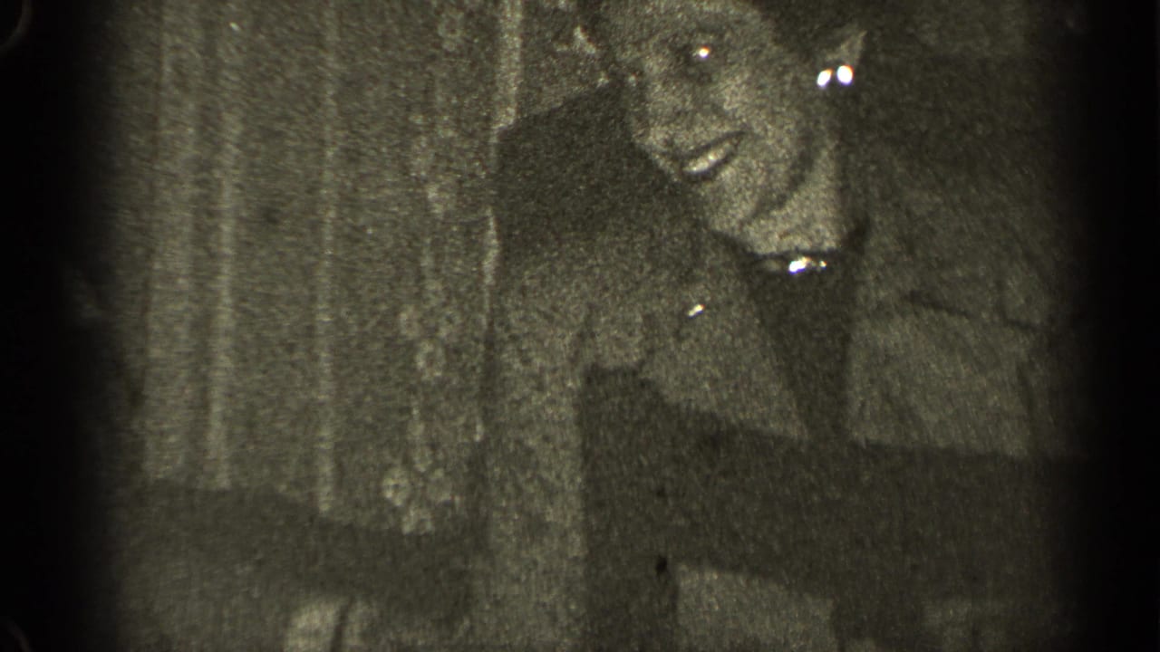 Grainy dark frame with an older person's face partly visible near the upper center.