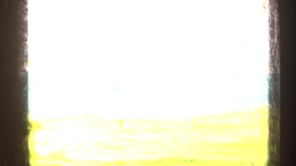 Overexposed 8mm frame with bright sky and a faint yellow-green field or shoreline band, with few clear details visible.