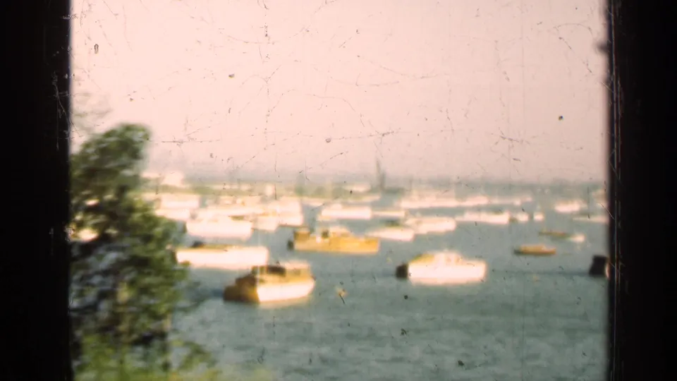 1947 Illinois 8mm frame showing moored boats on a lake or harbor, with trees and window framing in the foreground.