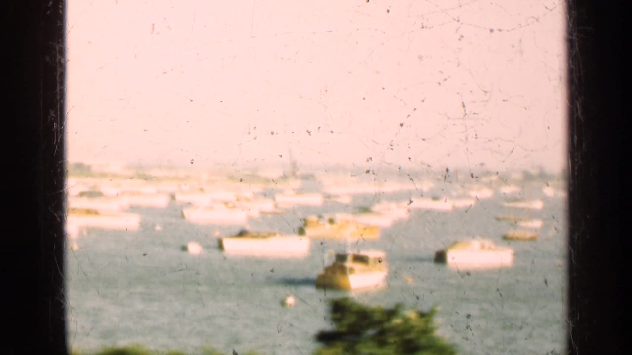1947 Illinois waterfront view with moored boats across the water, a hazy city edge, and vertical window framing in the foreground.