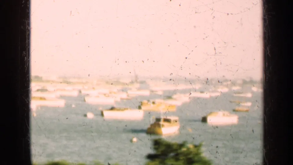 1947 Illinois waterfront view with moored boats across the water, a hazy city edge, and vertical window framing in the foreground.