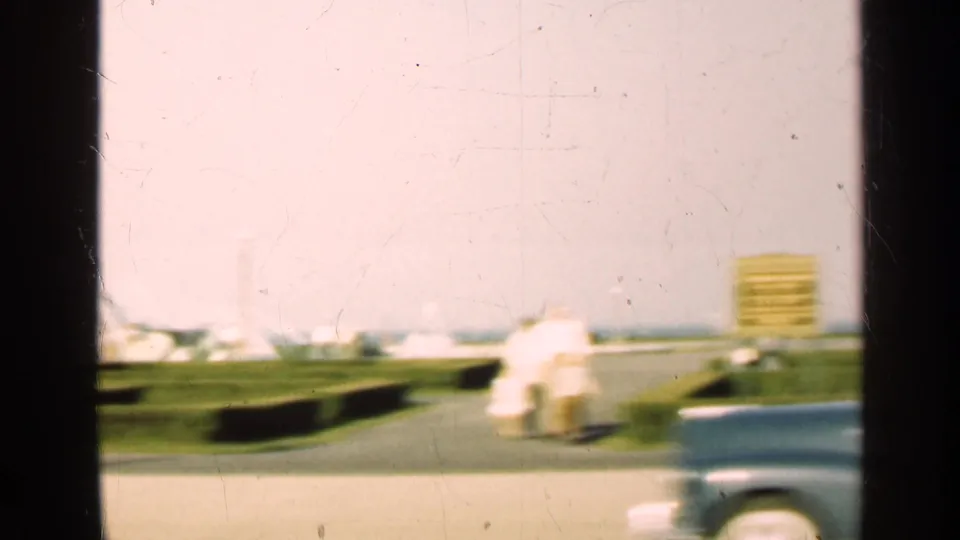 1947 Illinois roadside frame with fountain spray in the background, manicured grass, a sign-like object, and a passing car at the lower edge.