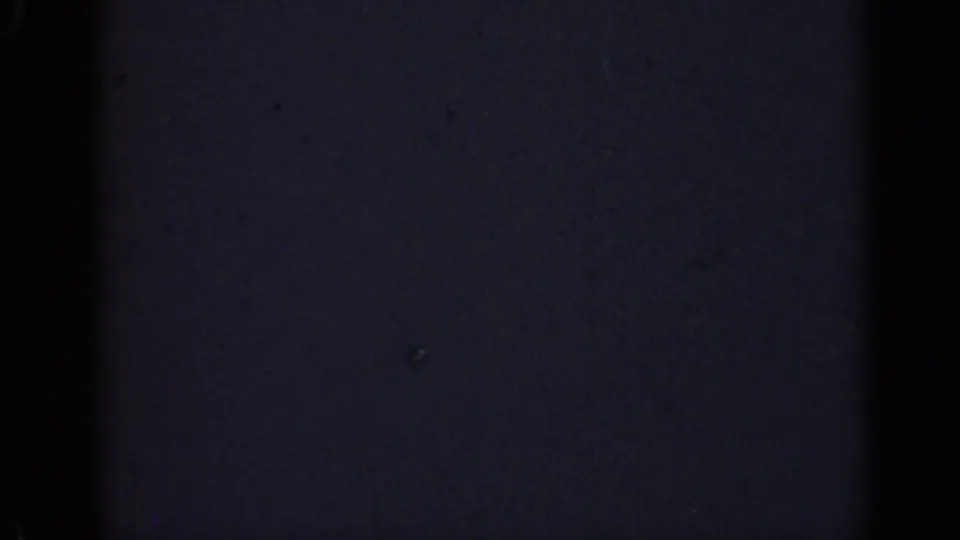 Underexposed 8mm frame from the 1947 Illinois clip, with darkness dominating and only faint grain and dust marks visible.