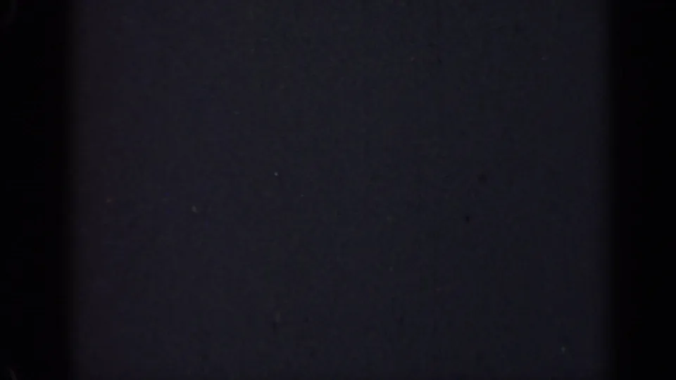 Mostly black 1947 Illinois 8mm home-movie frame with subdued grain, dust, and no identifiable subjects or landmarks.