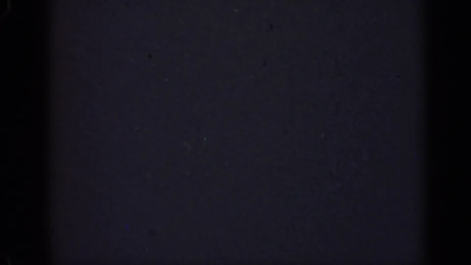 Final underexposed 1947 Illinois 8mm frame showing darkness with faint grain, dust specks, and no visible people or objects.