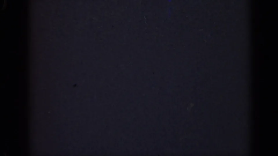 Dark 1947 Illinois 8mm home-movie frame with little visible subject detail beyond grain, vertical banding, and scattered dust specks.