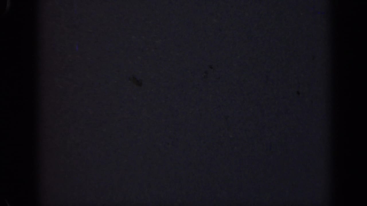 Underexposed 1947 Illinois 8mm frame with a broad central black band, low-detail dark surface, grain, and small film specks.