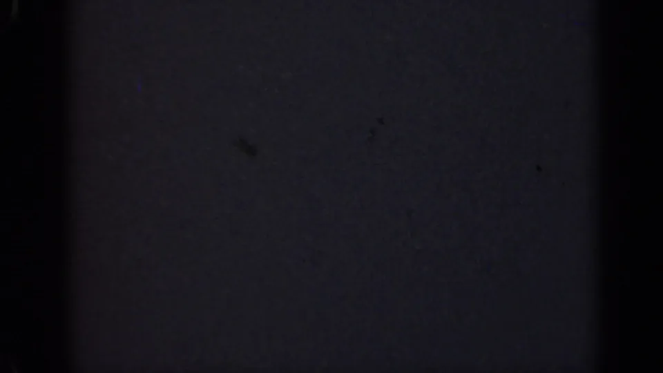 Underexposed 1947 Illinois 8mm frame with a broad central black band, low-detail dark surface, grain, and small film specks.