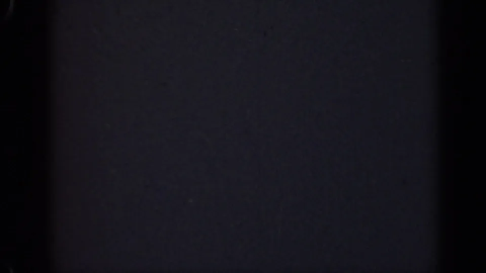 Nearly obscured 8mm frame from the supplied 1947 Illinois clip, showing vertical shadowing, subtle grain, and sparse bright specks.