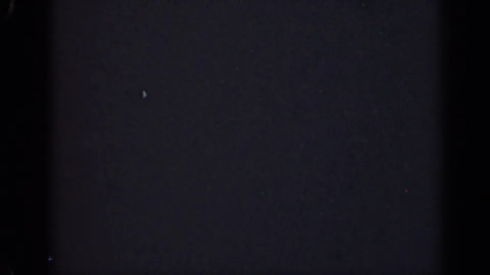 Dark 1947 Illinois 8mm frame with a broad vertical band, faint surface scratches, sparse specks, and no identifiable subject matter.