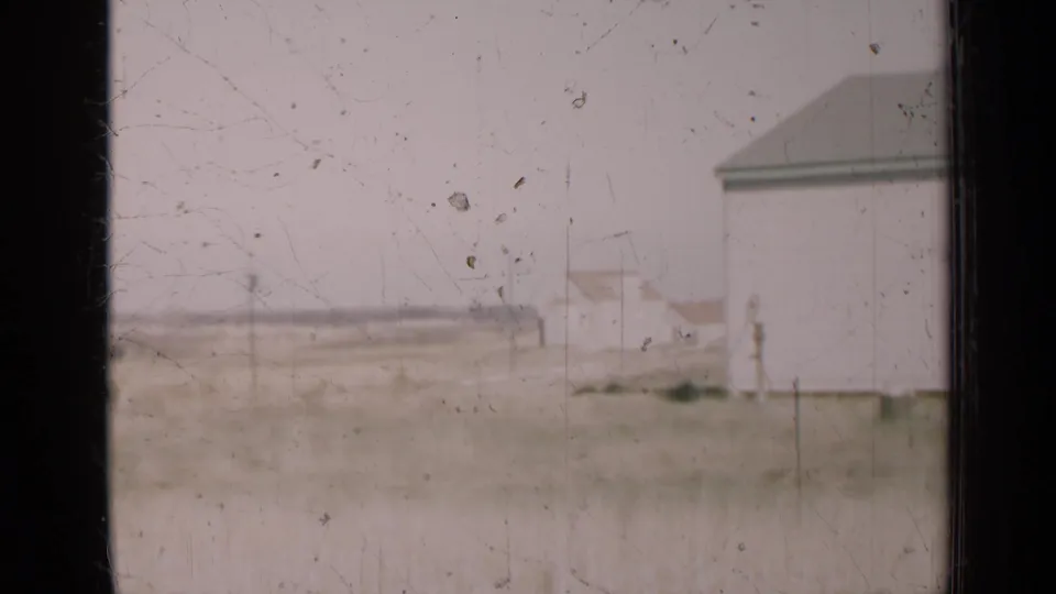 A white rural building appears near a dry field in 1947 Illinois 8mm home-movie footage.