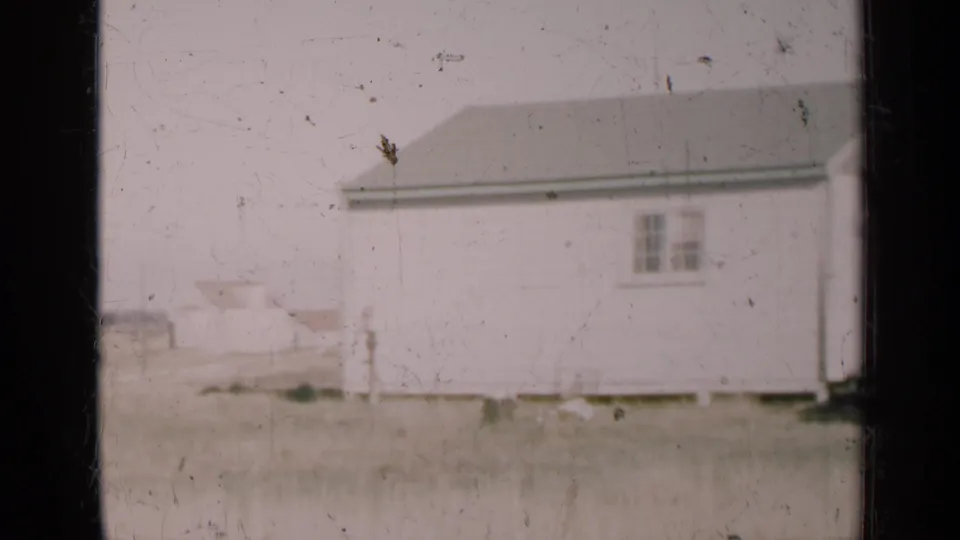 1947 Illinois 8mm frame showing a white rural building across a flat field, with no people visible.