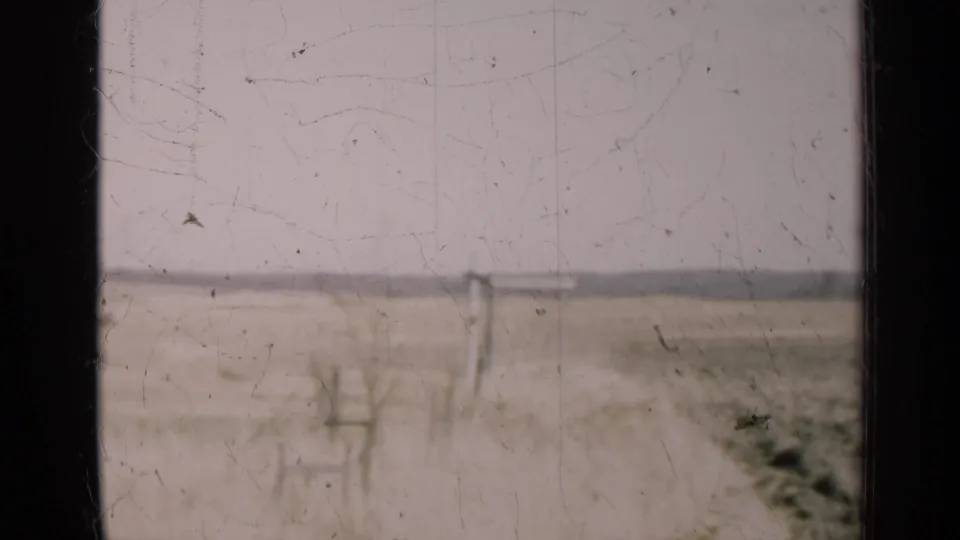 1947 Illinois home-movie frame showing open fields, a pale horizon, distant utility poles, and dark vertical window framing.
