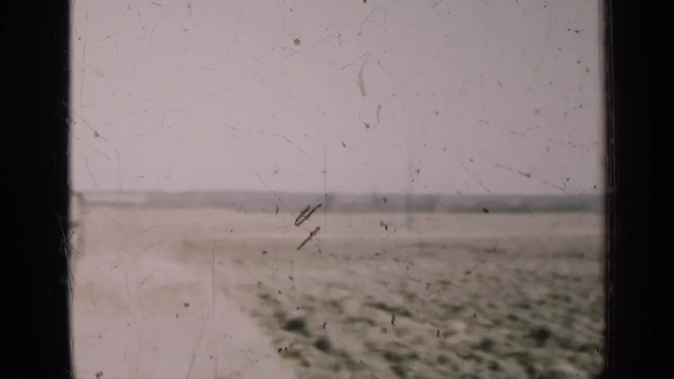 Rural Illinois landscape in 1947 with flat farmland, a pale sky, faint track lines, and dark window bars crossing the view.