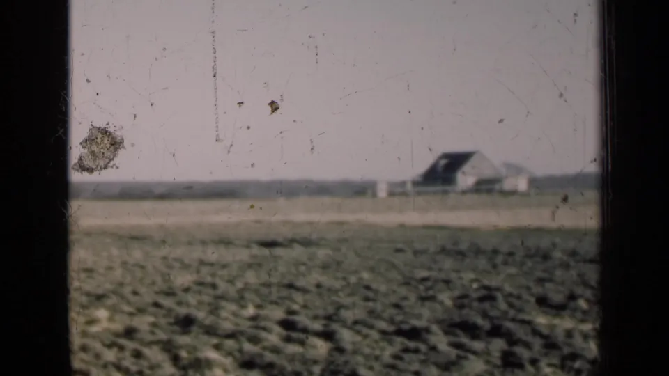 1947 Illinois countryside frame showing a flat field, low horizon, small distant farm building, and heavy film wear across the image.