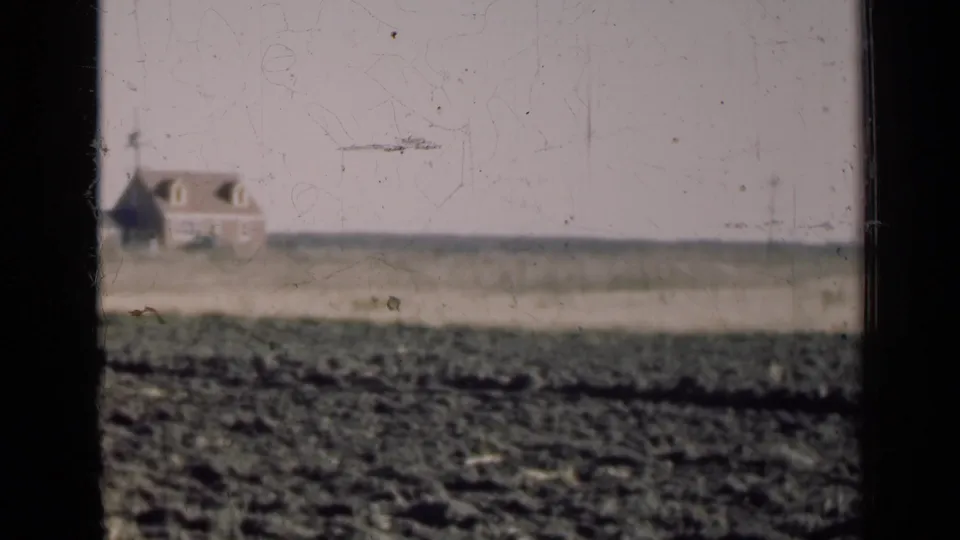 The rural farmhouse shifts toward the left edge of the 1947 Illinois frame as the vehicle continues past the field.
