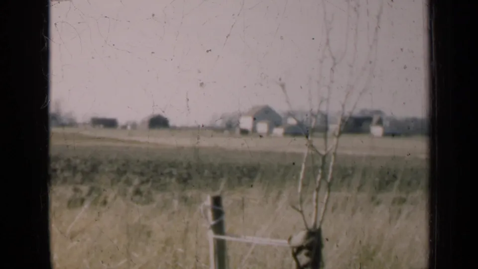 1947 Illinois rural landscape with distant house and barns viewed through a dusty dark-framed window.
