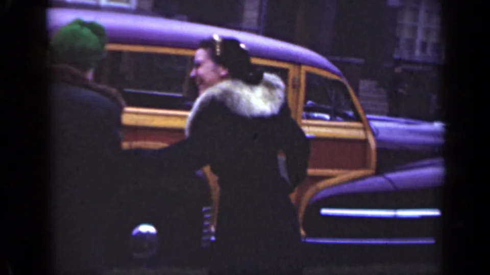 The women remain beside the vintage wood-panel station wagon on an Illinois street, framed from behind with brick buildings in the background.