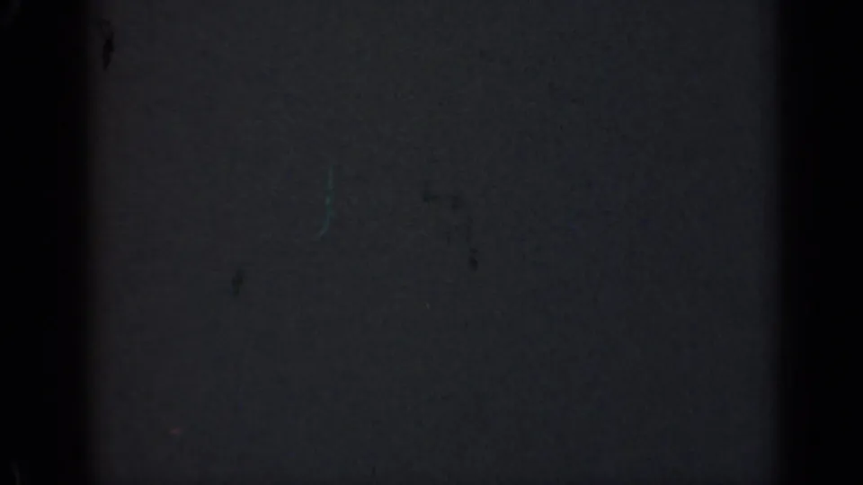 Dark 1947 Illinois 8mm home-movie frame showing mostly blank film surface, grain, dust marks, scratches, and dark vertical gate edges.