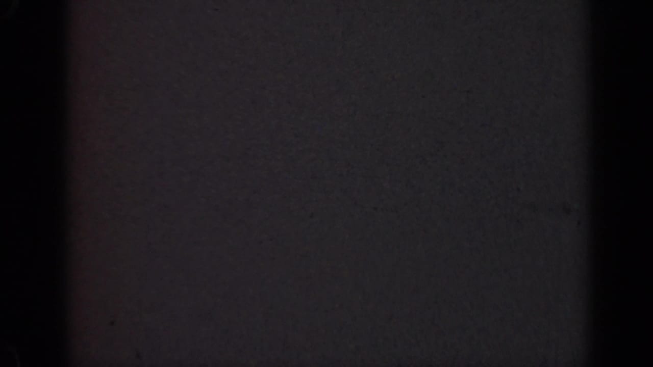 Underexposed 1947 Illinois 8mm frame with a broad black vertical obstruction and subtle red edge tint in the film scan.