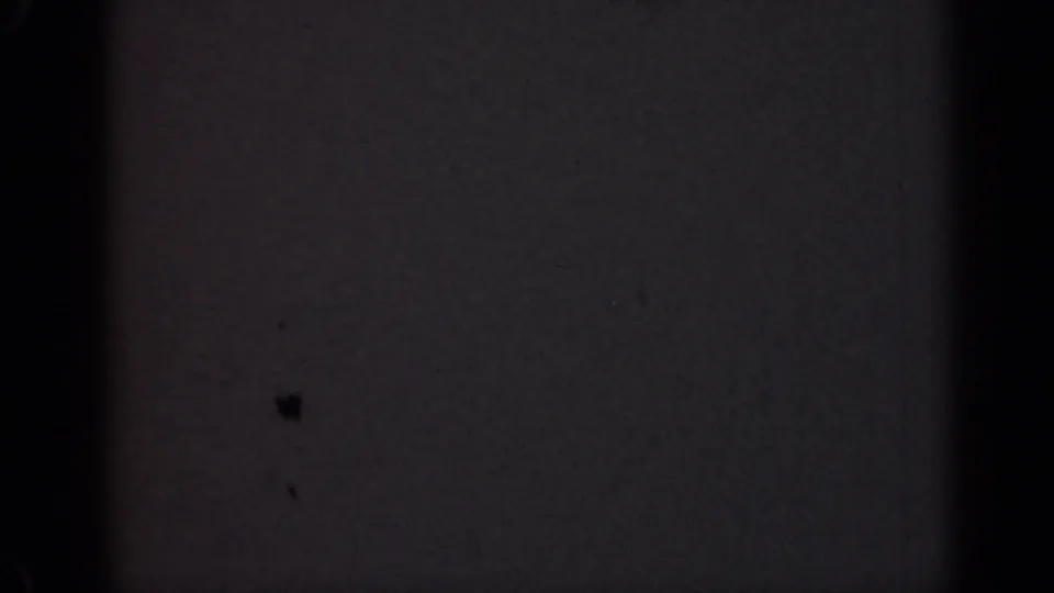Final dark 1947 Illinois 8mm frame with faint mottled grain, small dust marks, and black vertical edge obstruction.