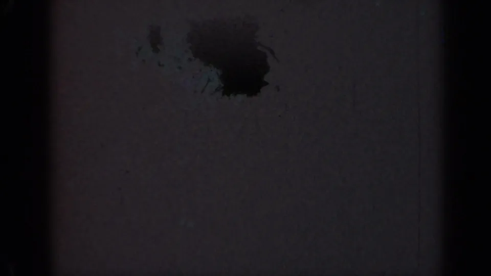 Damaged 1947 Illinois 8mm frame showing a dark stain near the upper right with grain, dust, and obscured exposure.