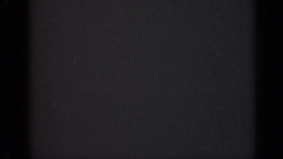Damaged 1947 Illinois 8mm home-movie frame with dim gray exposure, visible grain, dust, and dark vertical borders.