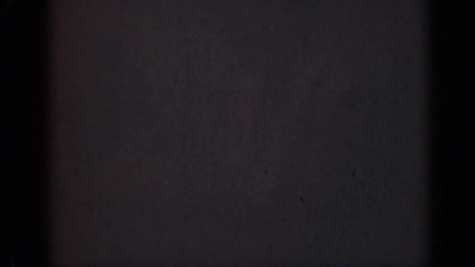 1947 Illinois 8mm home-movie frame showing darkness, grain, small specks, and a horizontal contact-sheet boundary.