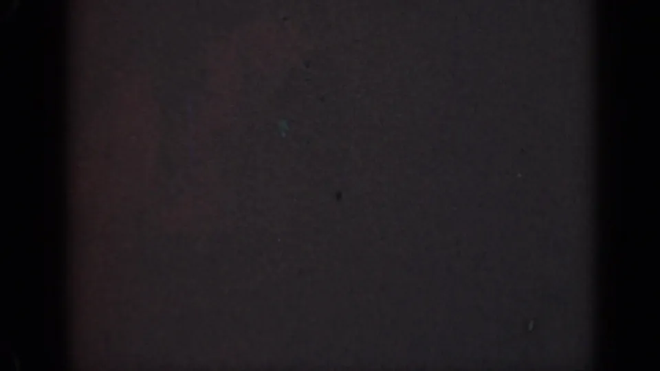 1947 Illinois 8mm home-movie frame with near-total darkness, faint red-blue color cast, and surface specks.