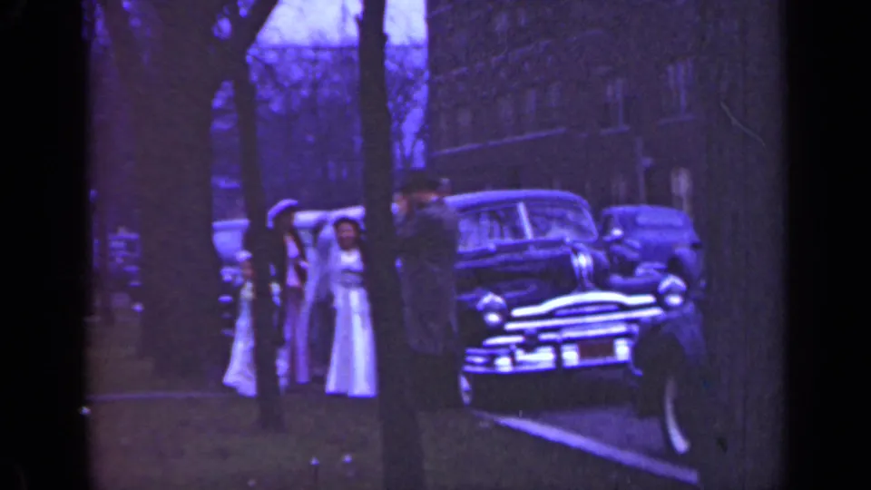 Illinois 1947 wedding departure scene with a bride in white, adults nearby, and a parked mid-century car under trees.