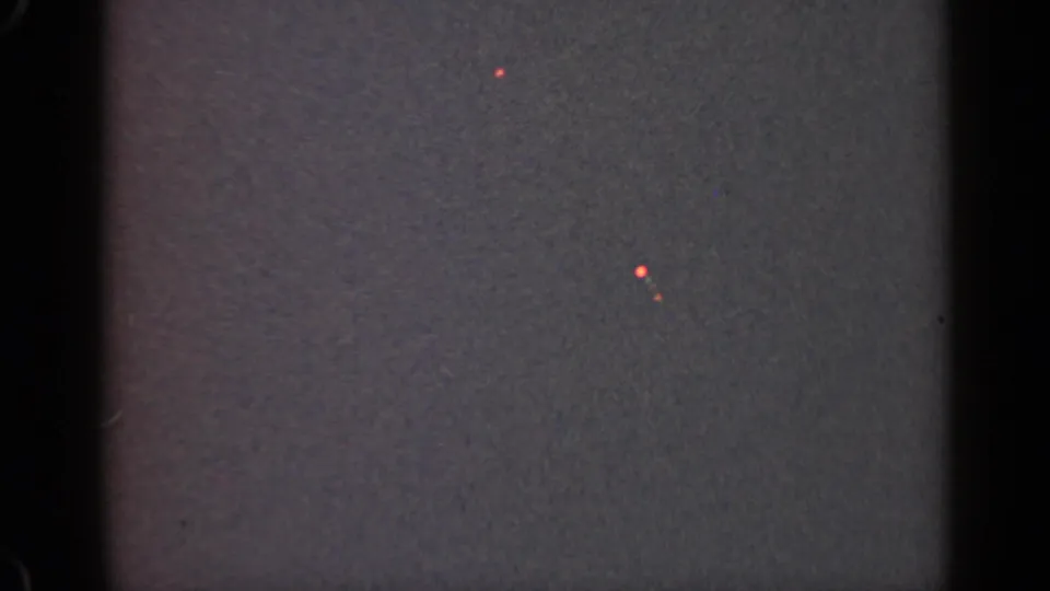 1947 Illinois 8mm frame showing mostly darkness, vertical film borders, grain, and scattered red-orange light spots.